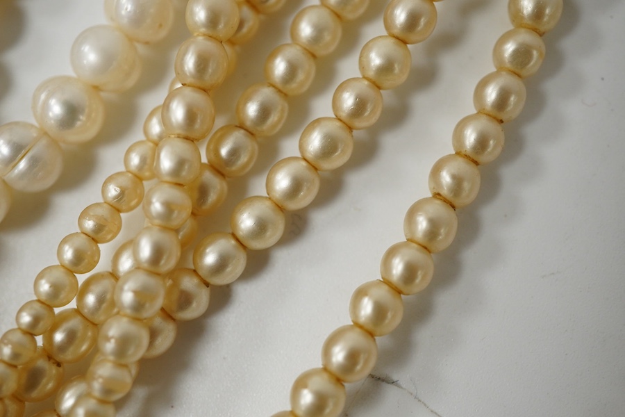 A collection of costume jewellery, comprising: a simulant pearl necklace with a green and colourless paste clasp; a fringe necklace set with circular-cut pastes; three strands of cultured pearls; a Royal Artillery cap ba